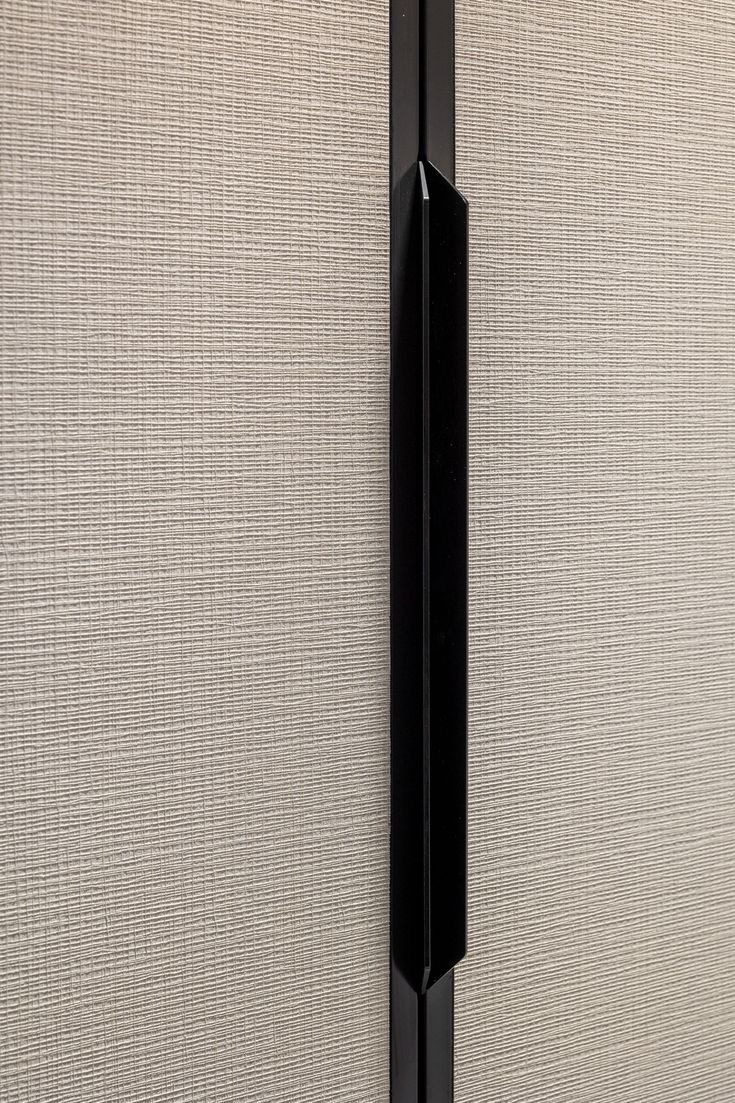 Détail d'une porte de dressing en panneau textile avec poignée verticale noire